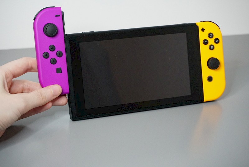 Die Nintendo Switch von vorne im Tisch-Modus. Der linke Joy-Con wird gerade rausgezogen.
