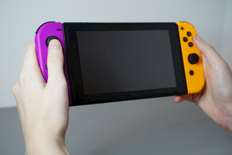 Die Nintendo Switch im Handheld-Modus. Sie wird von zwei Händen gehalten.
