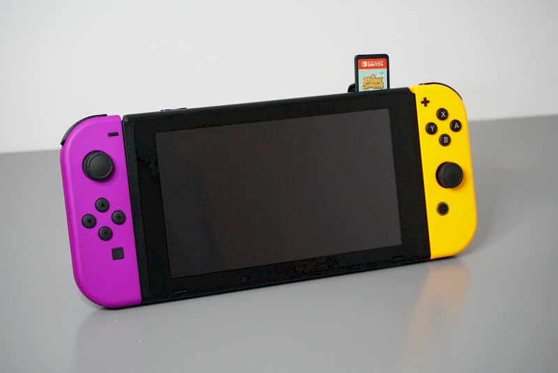 Ein Bild von der Nintendo Switch. Sie steht auf einem Tisch. Eine Game-Card ist oben rechts eingesteckt.