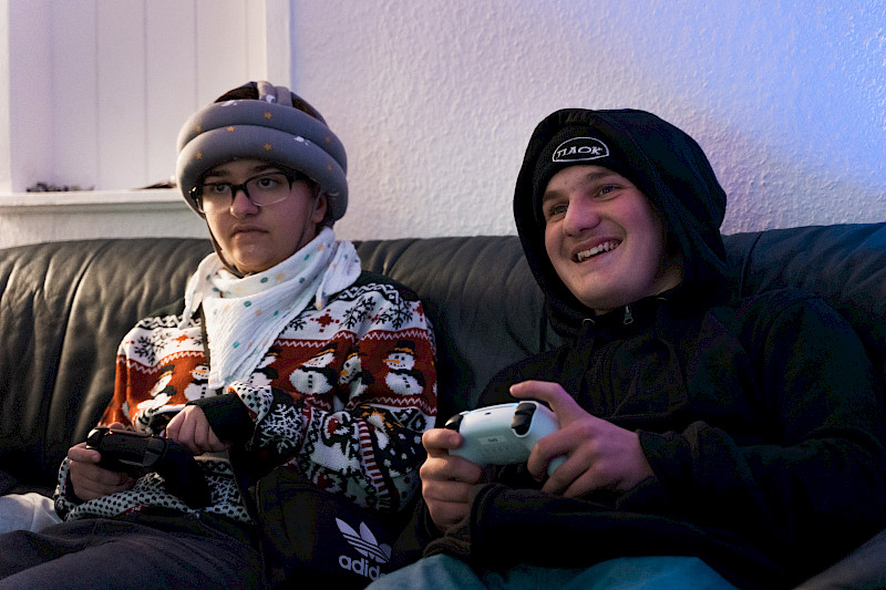 Zwei Spieletester sitzen zusammen auf der Couch und spielen mit Controllern