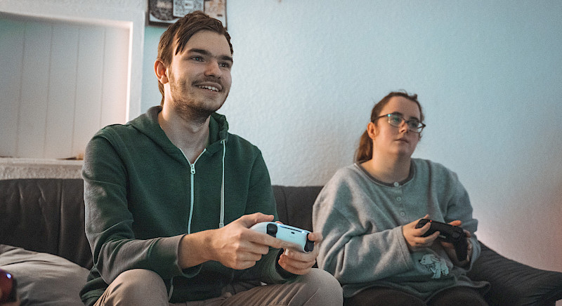 Ein Spieletester und eine Spieletesterin spielen gemeinsam auf einer Couch.