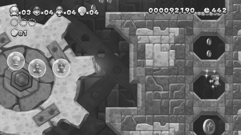 Ein Screenshot aus einem Level. Die Figur Toadette springt in einem Schloss. Links von ihr sind die Figuren Toad, Luigi und Mario jeweils in einer Blase. Das Bild ist in schwarz-weiß.