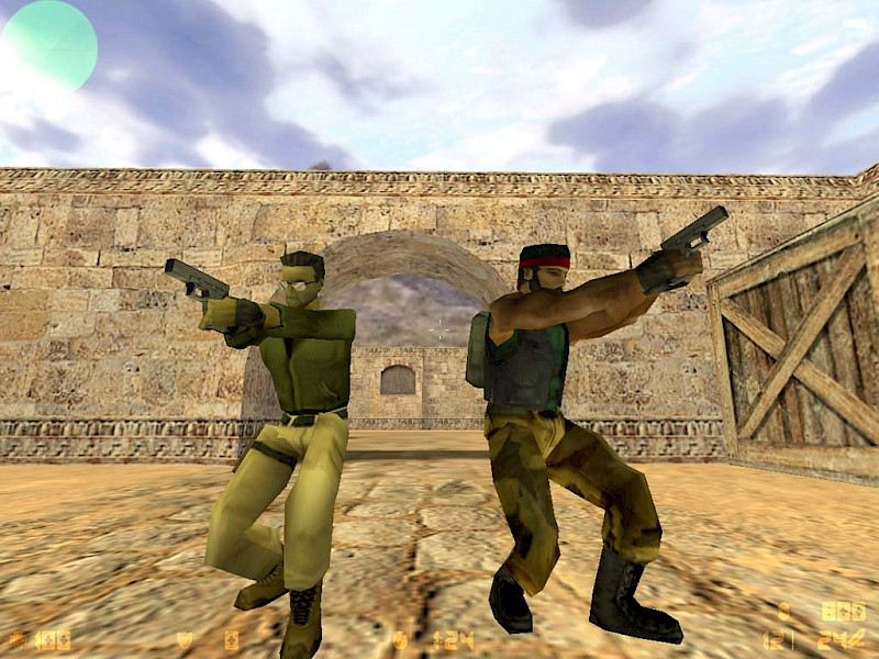 Zwei Personen mit Waffen stehen auf einem sandigen Untergrund. Die Grafik ist sehr pixelig.