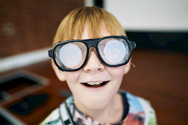 Ein Kind trägt eine Brille. Die Gläser sind mit Folien überklebt.
