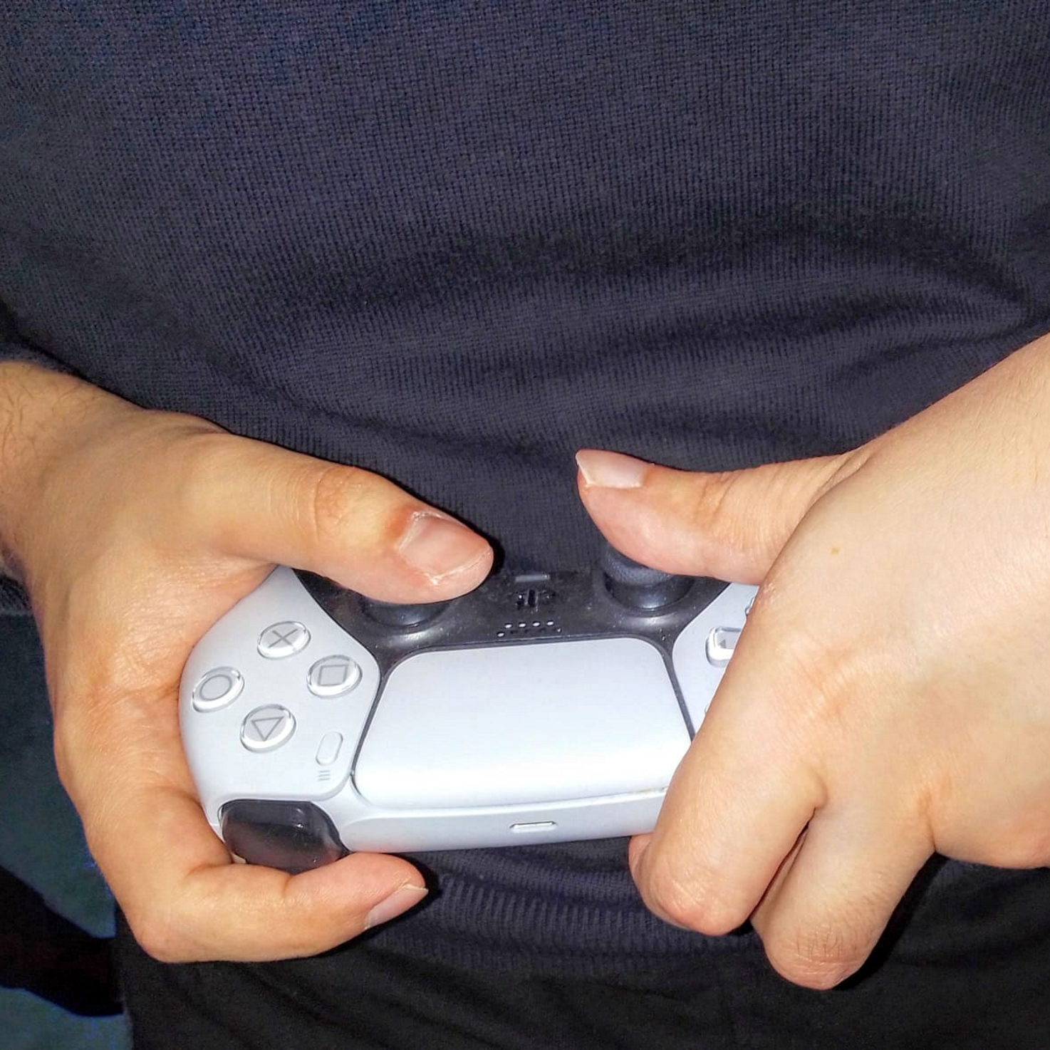Die Hände von Lukas halten einen PS5 Controller.