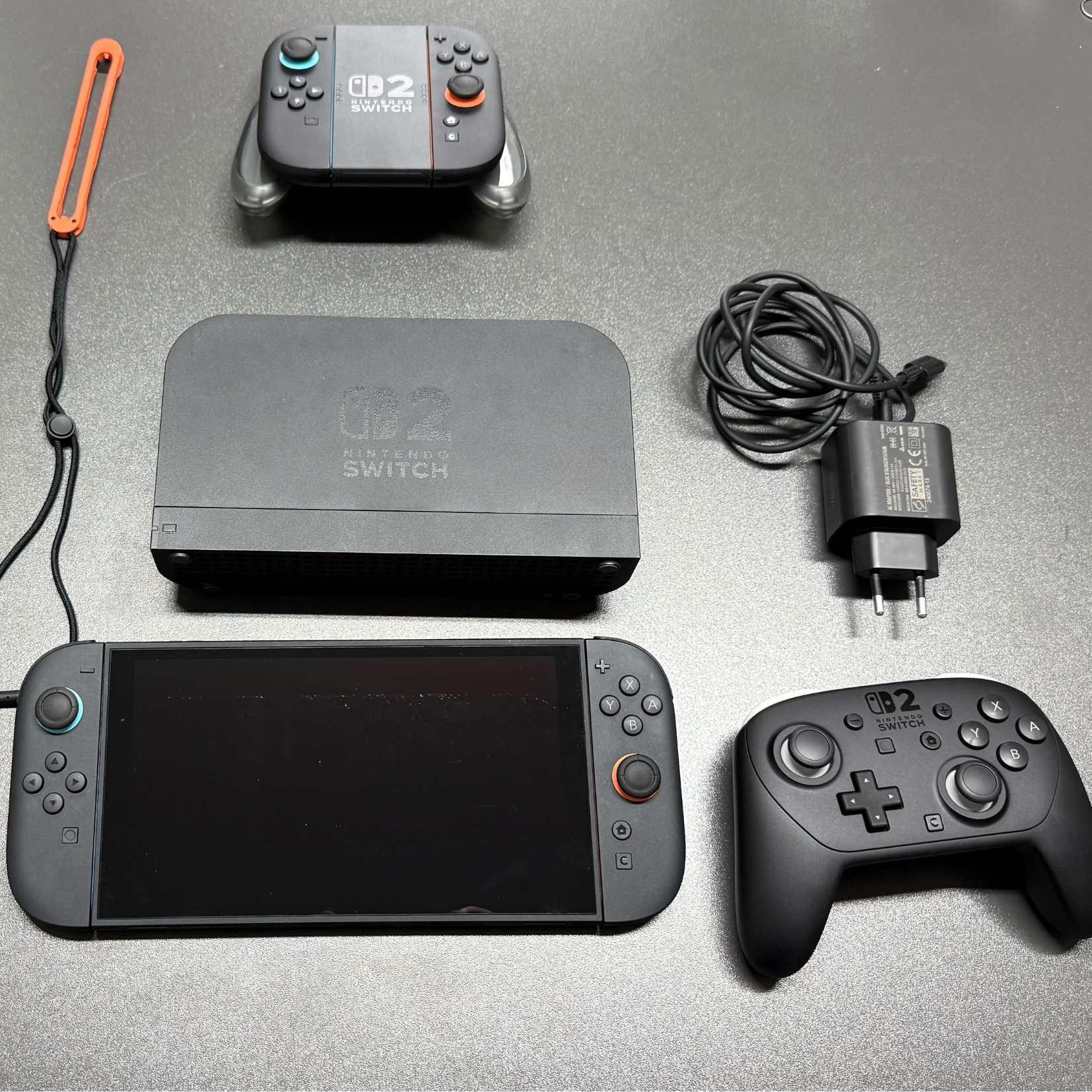 Die Nintendo Switch 2 liegt mit Controllern und Zubehör auf einem grauen Tisch