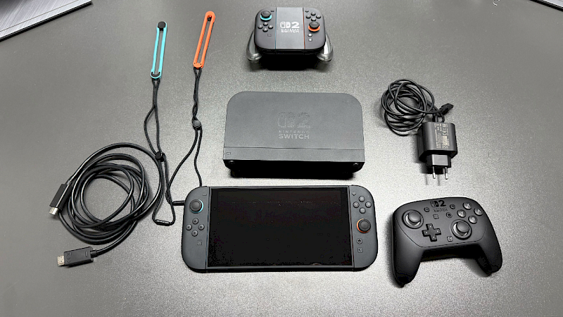 Die Nintendo Switch 2 liegt mit Controllern und Zubehör auf einem grauen Tisch